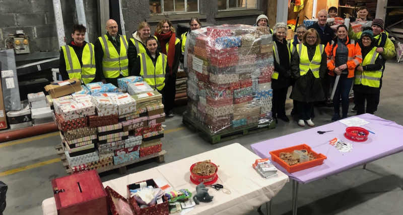 The team standing with the piles of shoeboxes ready to be sent away.